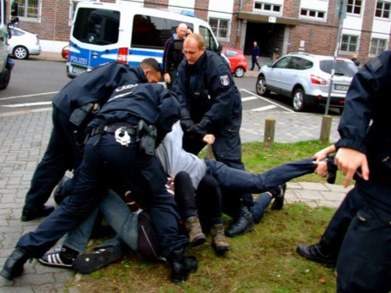 Bissiger Guineer außer Kontrolle, tritt, spuckt — Bild: Berlin Refugee Strike / Wikimedia (CC BY-SA 3.0)